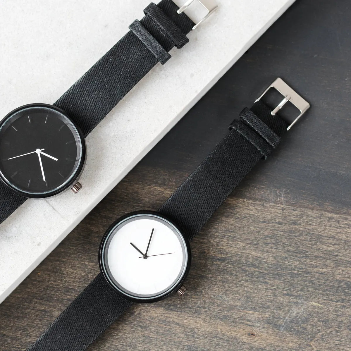 Deux montres à bracelet noir posées sur une table en bois