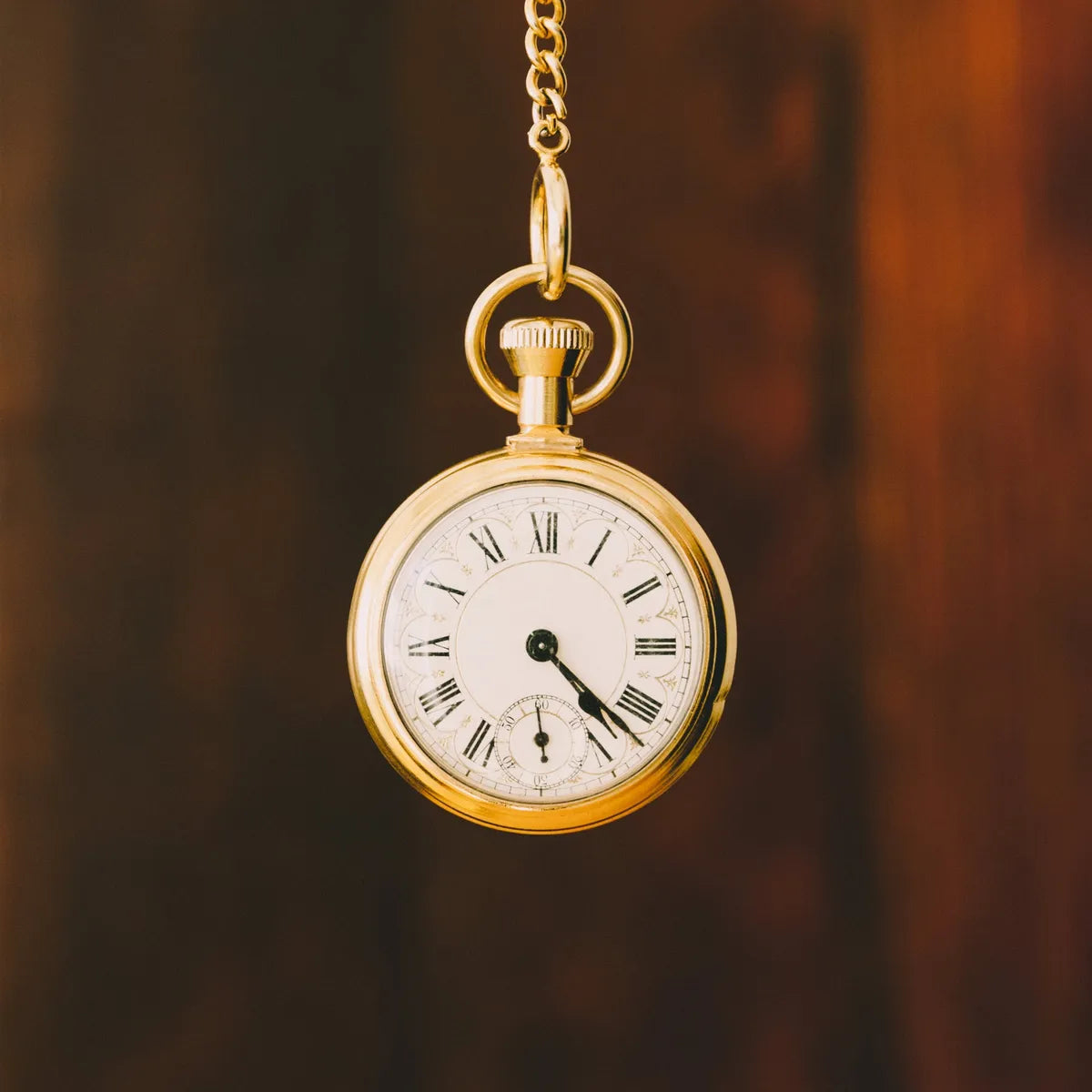 Montre à gousset dorée suspendue à sa chaîne